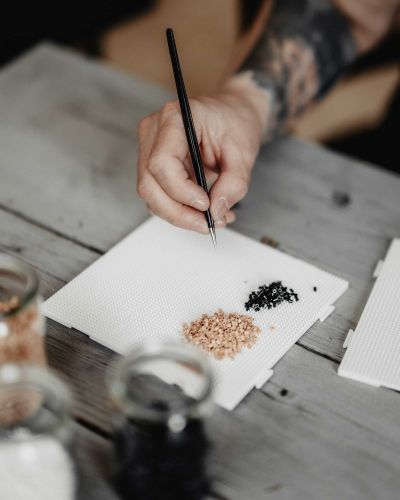 Ina Preu&szlig; h&auml;lt die Pinzette in der Hand und ist im Begriff, eine B&uuml;gelperle aufzugreifen, um Pixel f&uuml;r Pixel ein neues Kunstwerk zu schaffen.